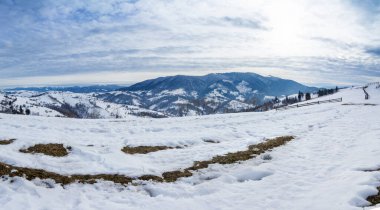 Karla kaplı dağ zirvesi rüzgarla esiyor. Kış manzarası. Güneşin altında parlayan karla soğuk bir gün..