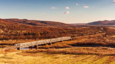 Ukrayna 'daki Stryi Nehri üzerindeki demiryolu köprüsünün havadan görüntüsü. Nehir boyunca uzanan güzel bir kırmızı demiryolu köprüsü, tepeler arasında muhteşem bir vadide yer alıyor. Yüksek kalite 4k