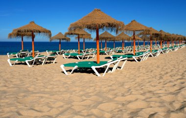 Plajda şemsiye ve güneş şezlong