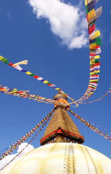 Stupa avec des yeux de bouddha et des drapeaux de prière sur fond bleu ciel clair — Photo