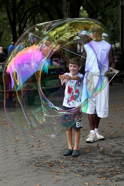 Niet-geïdentificeerde performer en kinderen spelen met zeepbellen op centra — Stockfoto