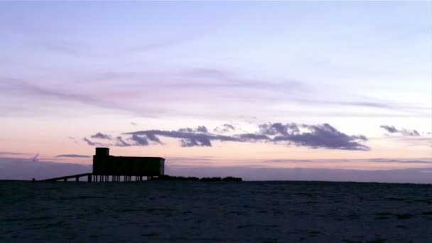 Západ slunce a historické plavčík budova v popředí, na fuseta rybářské městečko, ria formosa památkově chráněný park, algarve. Portugalsko — Stock video