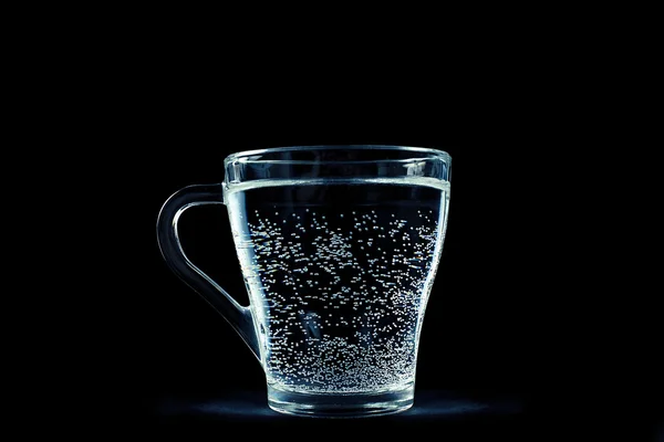 Glas vatten med bubblor på svart bakgrund Stockfoto