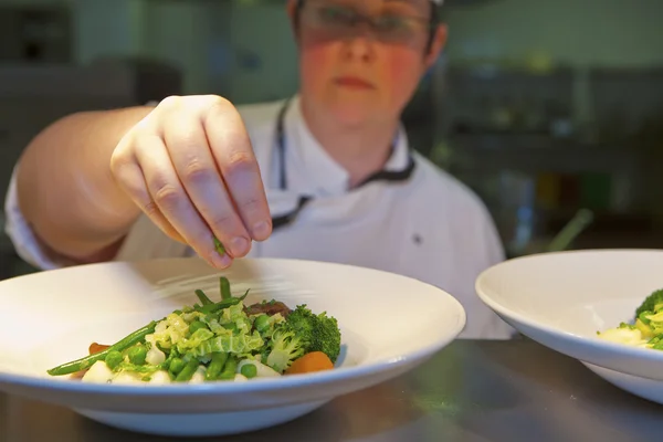 Close-up van chef-kok finishing touch toe te voegen op zijn schotel — Stockfoto