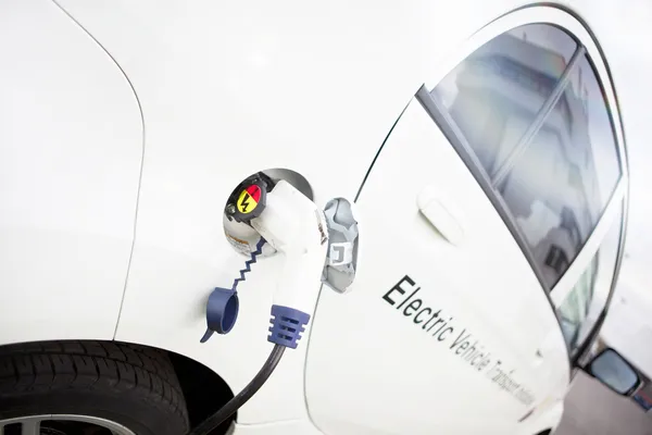 Carro elétrico branco que carrega exterior — Fotografia de Stock