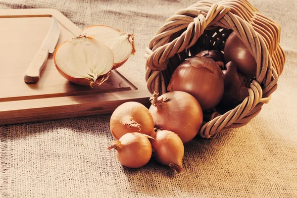 Loose onions scattered from wicker basket — Stock Photo, Image