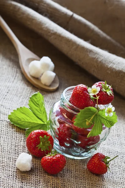Rode aardbeien in glazen pot op rouwgewaad — Stockfoto