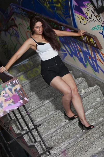 Young pretty girl posing in abandoned graffity painted building — Stock Photo, Image