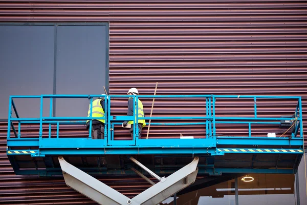 Bouwer op een schaar lift platform op een bouwplaats — Stockfoto