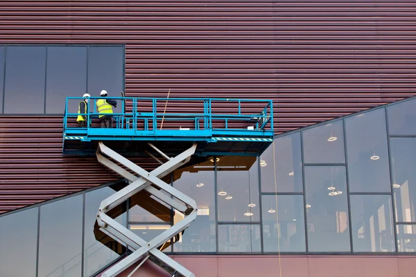Builder on a Scissor Lift Platform at a construction site — Stock Photo, Image