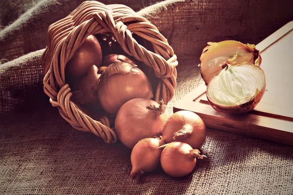 Luźne cebuli rozrzucone z wikliny kosz — Zdjęcie stockowe