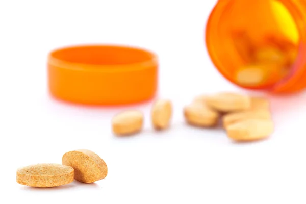 Closeup of orange pills and pill bottle — Stock Photo, Image