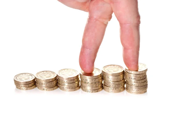 Fingrar gå på högar av ett pund mynt — Stockfoto