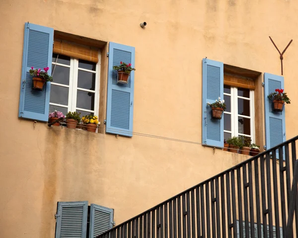 Fönster med blå fönsterluckor på beige väggar i marseille — Stockfoto