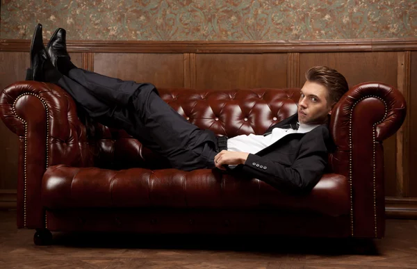 Un hombre con un traje acostado en el sofá —  Fotos de Stock