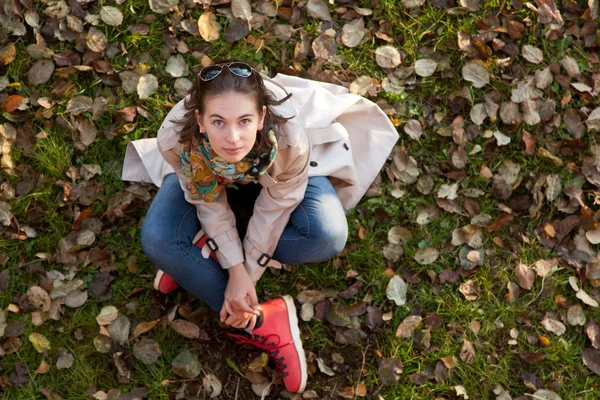 Mädchen sitzt auf den Herbstblättern — Stockfoto