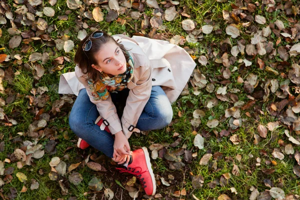 Девушка, сидящая на осенних листьях — стоковое фото