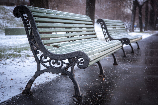 Green bench in winter and falling snow, soft focus