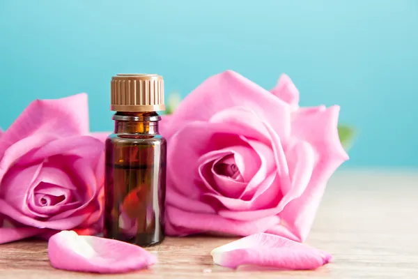 Láhev s aromatickým olejem a růžové růže — Stock fotografie