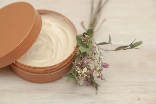 Body cream and wildflowers on wooden table — Stock Photo, Image