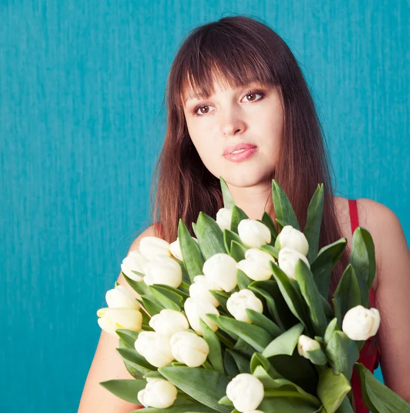 Mladá žena s kyticí tulipánů na modrém pozadí — Stock fotografie