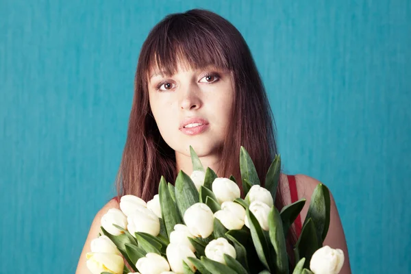 Young woman with a bouquet of tulips on a blue background — Stock Photo, Image
