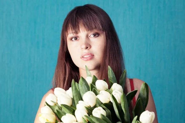 Young woman with a bouquet of tulips on a blue background Royalty Free Stock Images