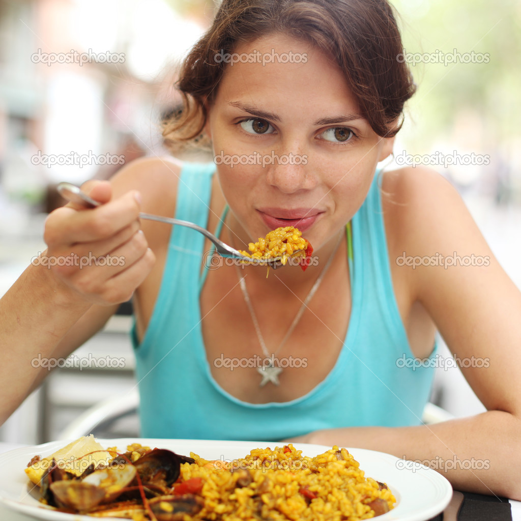 young woman eating paella in a cafe