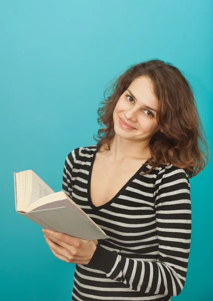 Portrait d'une jeune femme avec un livre sur fond bleu — Photo
