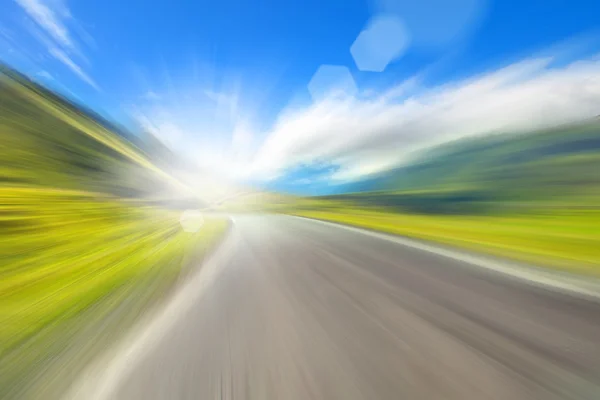 Strada in montagna, immagine sfocata con luce solare — Foto Stock