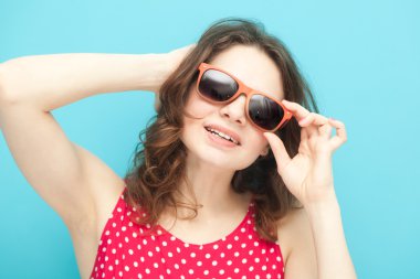 yumuşak odak mavi bir arka plan üzerinde güneş gözlüğü güzel kız