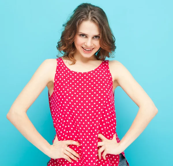 Gadis cantik dalam blus merah dengan titik-titik polka pada backgro biru — Stok Foto