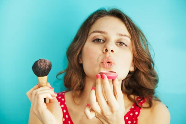 Beautiful girl with a brush and blusher on a blue background in — Stock Photo, Image