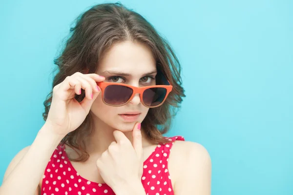 Bella ragazza in occhiali da sole su uno sfondo blu a fuoco morbido — Foto Stock