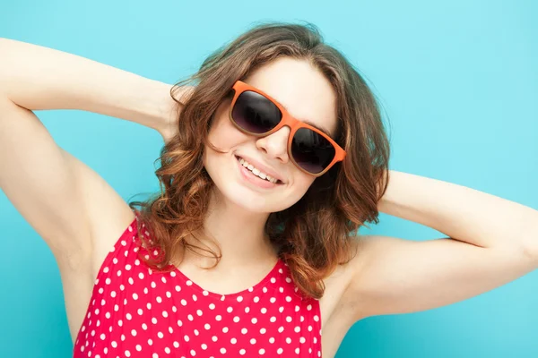 Belle fille dans des lunettes de soleil sur un fond bleu dans la mise au point douce — Photo