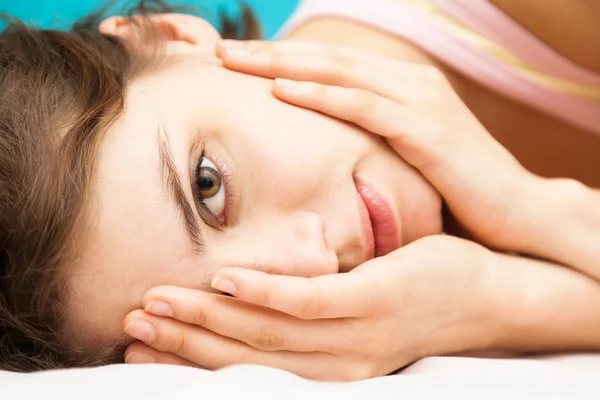 Beautiful young woman lying on the bed and looking at the camera — Stock Photo, Image