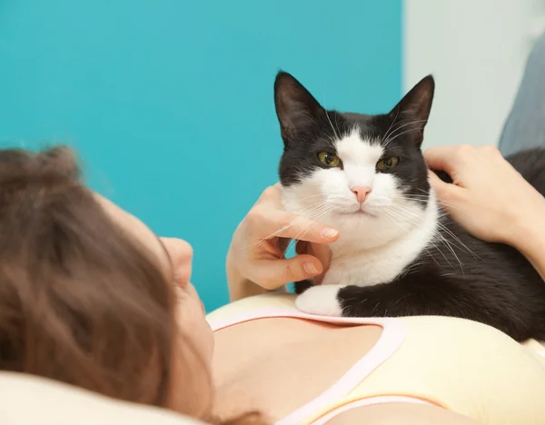 Jeune femme avec un chat noir et blanc au foyer doux dans le dos — Photo