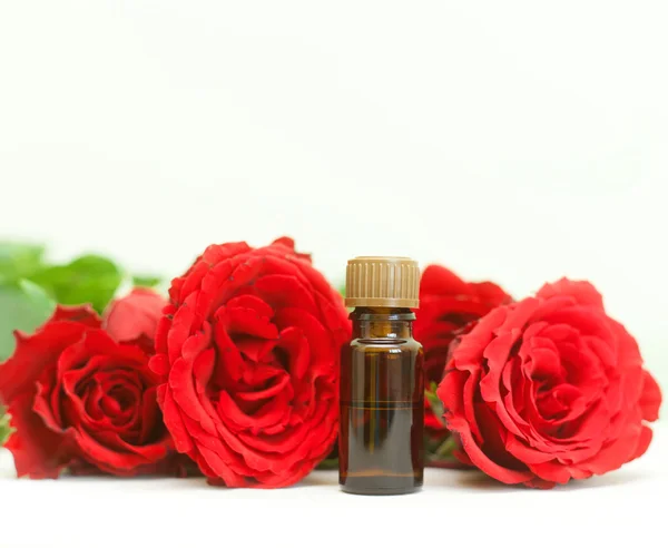 Bottle of aromatherapy oil and bright red roses, beauty spa Royalty Free Stock Images