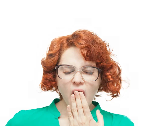 Рыжая девушка в очках зевает на белом фоне — стоковое фото
