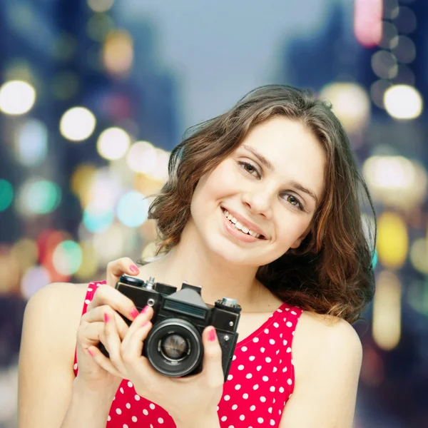 Menina bonita com câmera de foto vintage no fundo da noite em — Fotografia de Stock