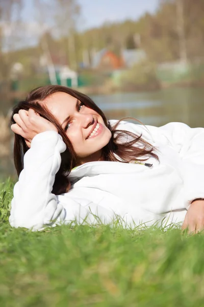 Frau im weißen Sweatshirt im Gras liegend — Stockfoto