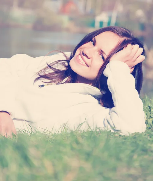 Vrouw in een witte trui liggen op het gras — Stockfoto