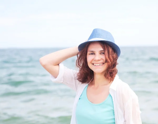 Mooi meisje in een hoed op een achtergrond van de zee, in zachte focu — Stockfoto