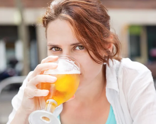 Menina bonita bebendo cerveja do copo em um café — Fotografia de Stock