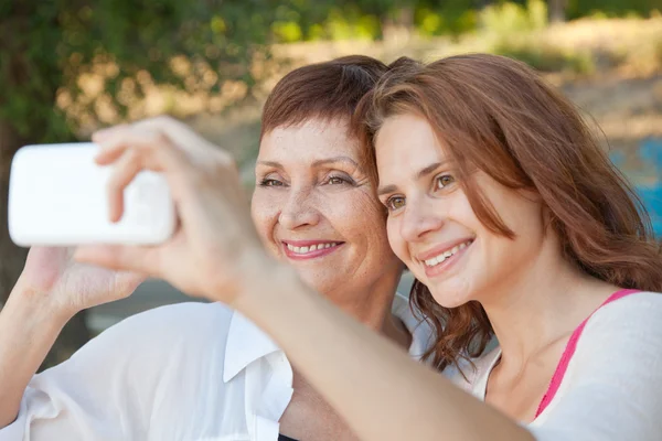 Äiti ja aikuinen tytär tekevät selfie puhelimessa — kuvapankkivalokuva