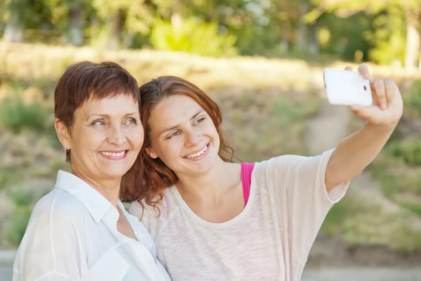 Äiti ja aikuinen tytär tekevät selfie puhelimessa — kuvapankkivalokuva