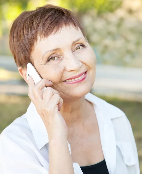 Piękna kobieta 50 lat z telefonu komórkowego na zewnątrz — Zdjęcie stockowe