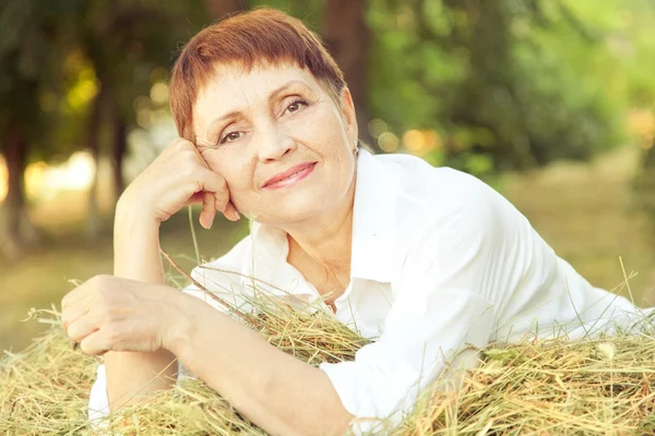 Schöne Frau 50 Jahre auf dem Heuhaufen, im Freien — Stockfoto