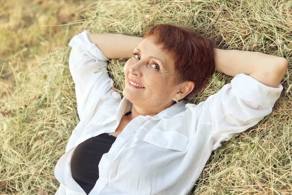 Красивая женщина 50 лет на стоге сена, на открытом воздухе — стоковое фото