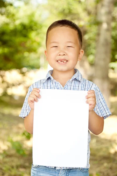 Азиатский мальчик 6 лет с листом бумаги в парке — стоковое фото